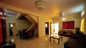 A spacious living room with a staircase, a dining area, and a sofa. - Savitri Bungalow (Jaoli)