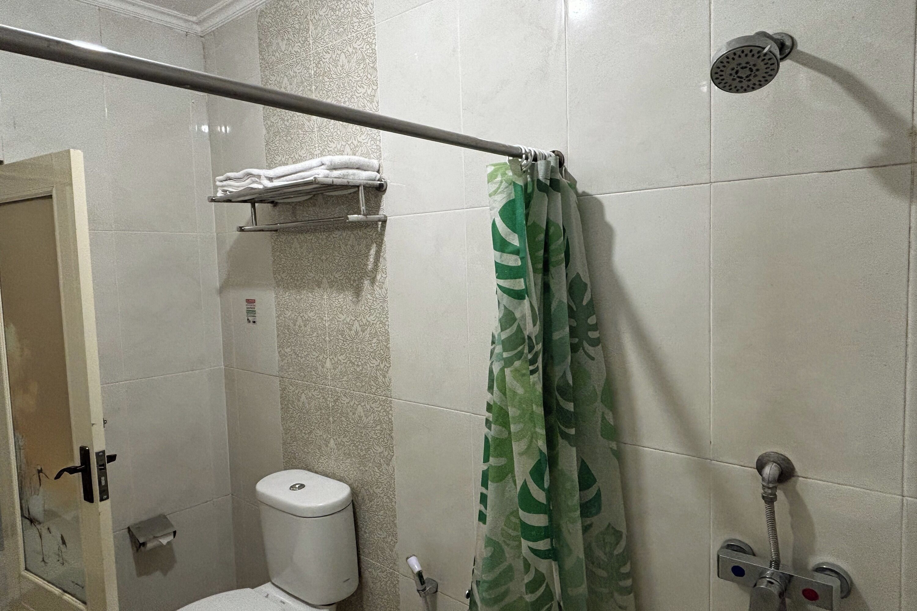 A bathroom with a shower, toilet, and a towel rack.
