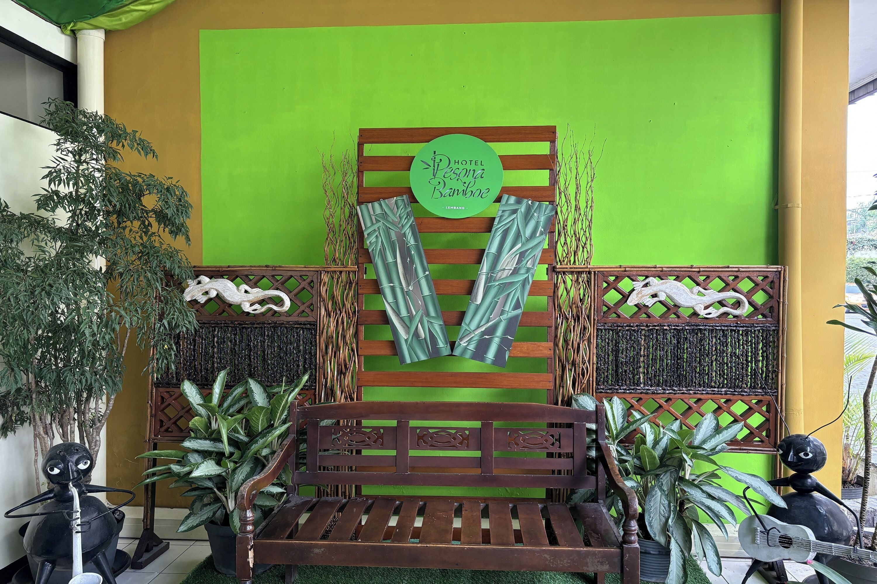 Un banco de madera con un fondo verde, un letrero que dice "Hotel Pesoma Barine" y paneles decorativos con motivos vegetales.