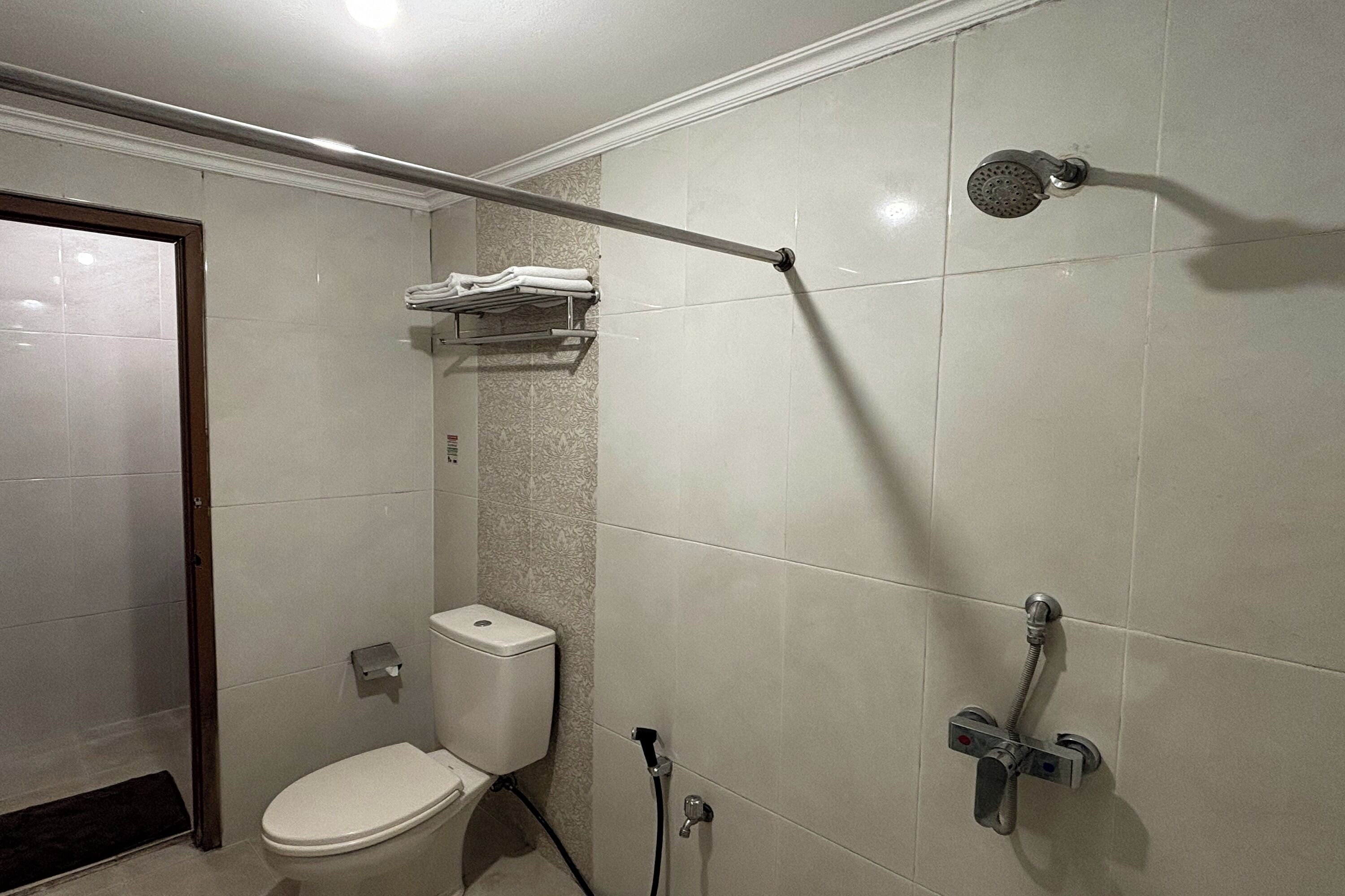 A small, modern bathroom with a toilet, a shower, and a towel rack.