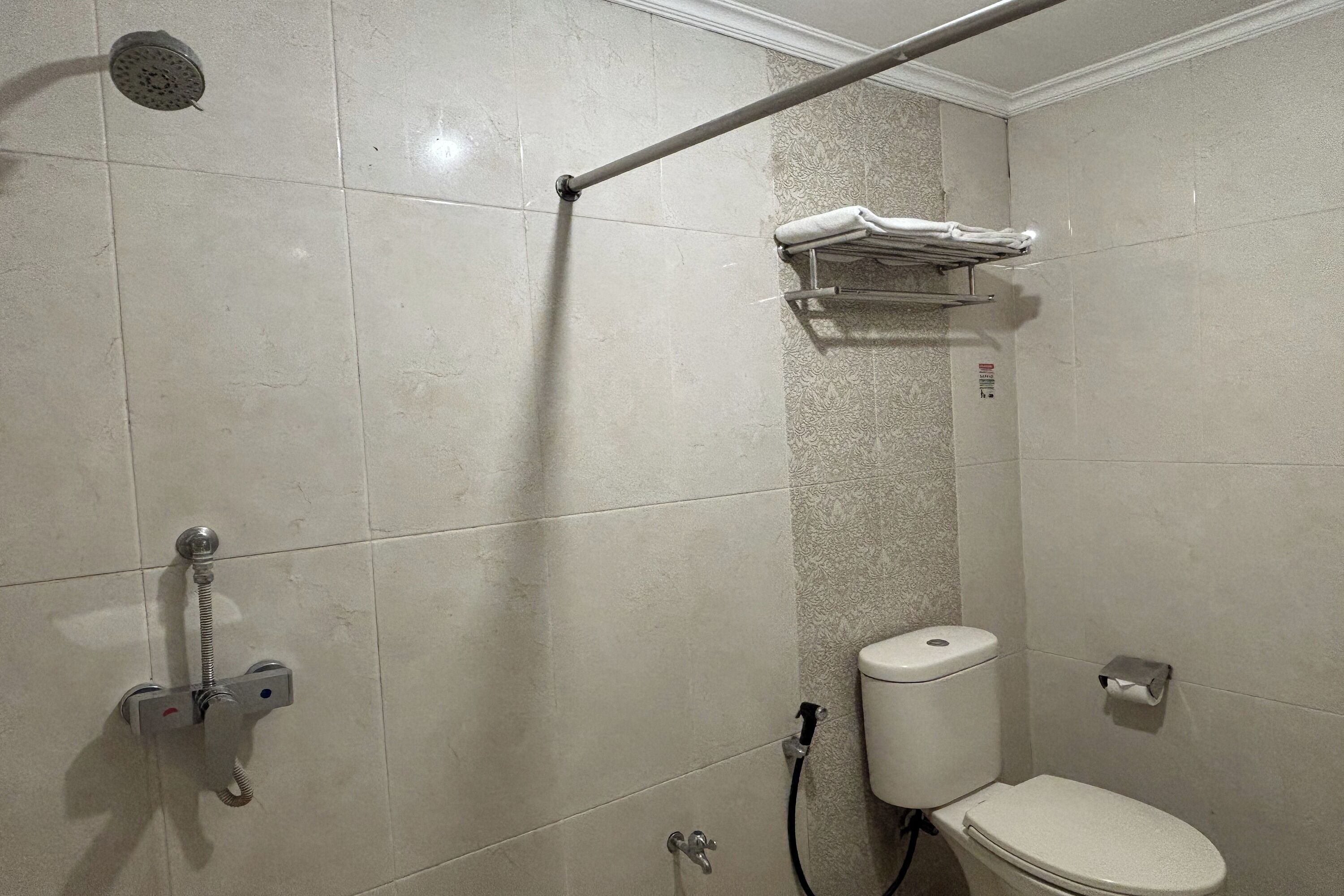A bathroom with a shower, toilet, and towel rack.