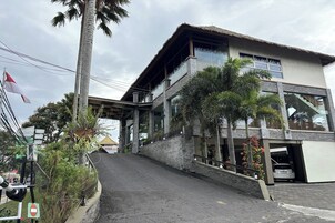 Un edificio moderno con estructura de dos pisos, entrada cubierta y área de estacionamiento.