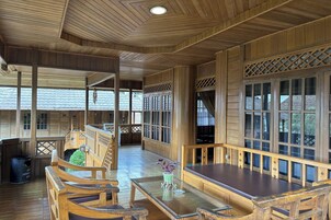 Interior de madera con techo alto, bancos de madera, una mesa y vistas amplias por ventanas grandes.