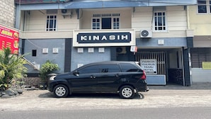 Un bâtiment avec une enseigne indiquant « KINASIH » et une autre indiquant « PARC DE STATIONNEMENT RÉSERVÉ AUX CLIENTS DE L’HÔTEL KINASIH », ce qui indique qu’il s’agit d’un hôtel.