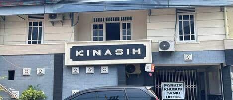 Un edificio con un cartel que dice "KINASIH" y otro cartel que indica "PARKIR KHUSUS TAMU HOTEL".