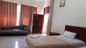 A hotel room with two beds, a sofa, a wooden door, and a window with curtains.