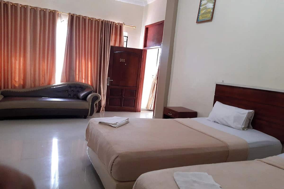 Habitación de hotel con dos camas, un sofá, una puerta de madera y una ventana con cortinas.