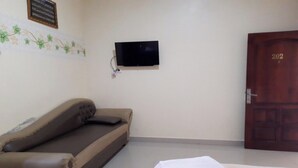 A room with a sofa, a television mounted on the wall, and a door with the number 202.