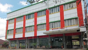 A multi-story building with a red and white facade, large windows, and a covered entrance area.