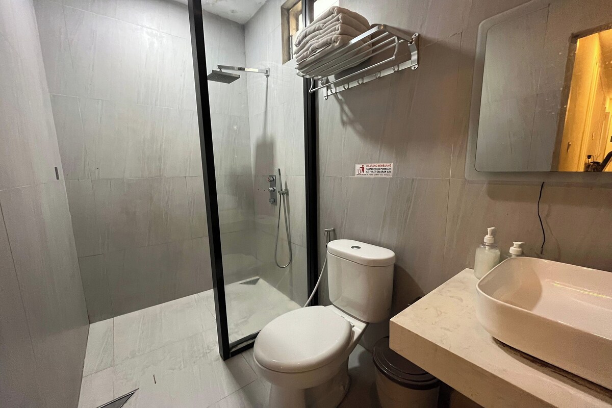 A bathroom with a toilet, a sink, a glass shower enclosure, and a towel rack.