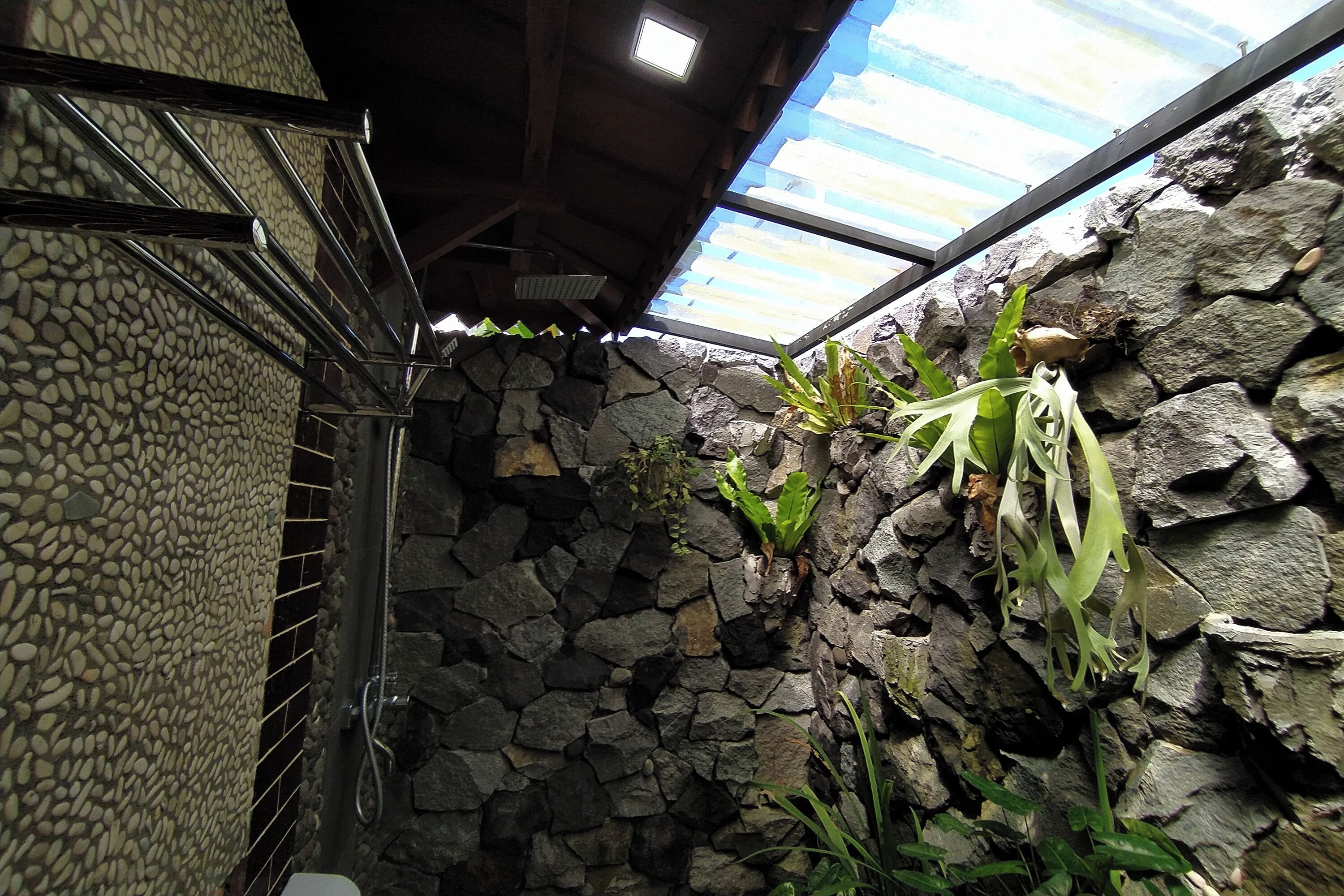 A bathroom with a stone wall, a shower area, and a skylight.