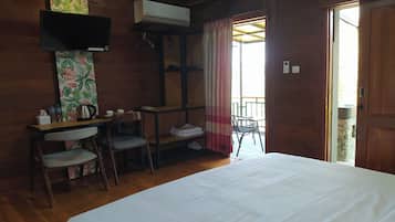 Una habitación de madera con cama, un escritorio con sillas, aire acondicionado y televisor.
