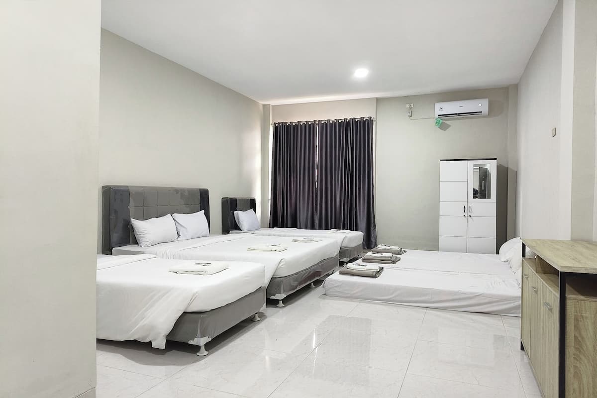 A hotel room with two beds, a wardrobe, and an air conditioning unit.