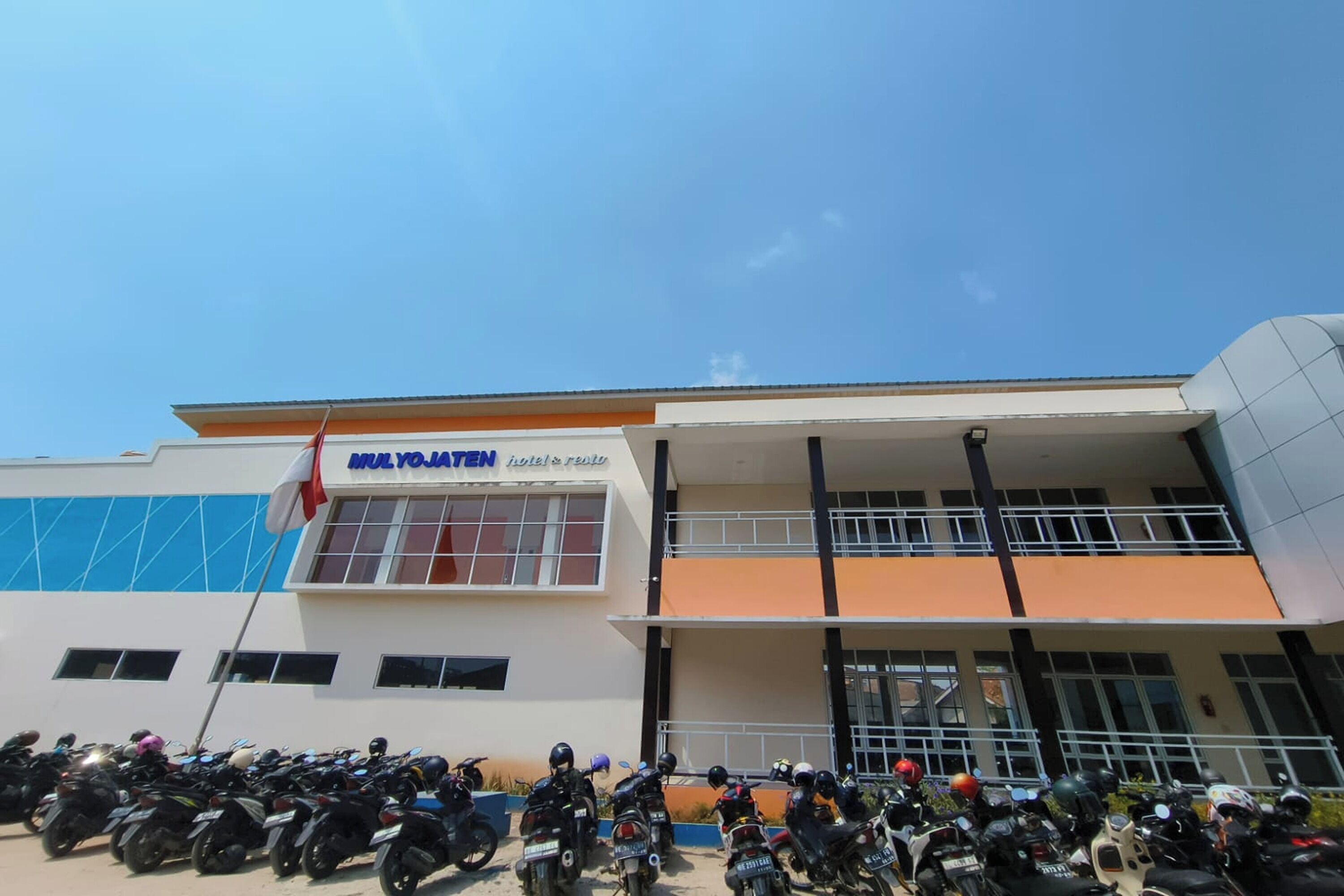 Un edificio con un cartello che riporta la scritta "MULY YOJATEN" e una fila di motociclette parcheggiate davanti.