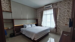 Un dormitorio moderno con una cama grande, estanterías empotradas, un escritorio y un televisor.
