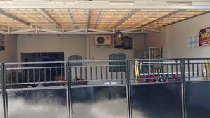 A covered outdoor area with metal railings, an air conditioning unit, and a sign for a restaurant. - Pondok Family (Pangandaran)