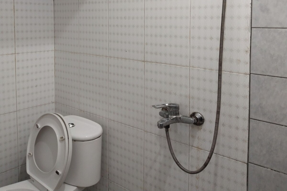 A bathroom with a toilet, a shower, and tiled walls.