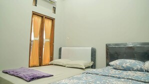 A bedroom with a bed, a window with curtains, an air conditioning unit, and a wardrobe. - Pondok Family (Pangandaran)