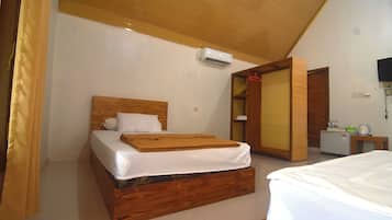 Un dormitorio con cama de madera, ropa de cama blanca, un equipo de aire acondicionado, una mesita de noche pequeña y un armario.