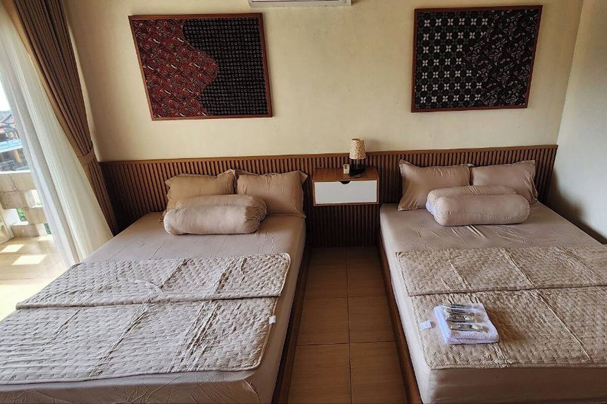 Ein Hotelzimmer mit zwei Betten, einem Nachttisch und zwei an der Wand befestigten Kunstwerken.