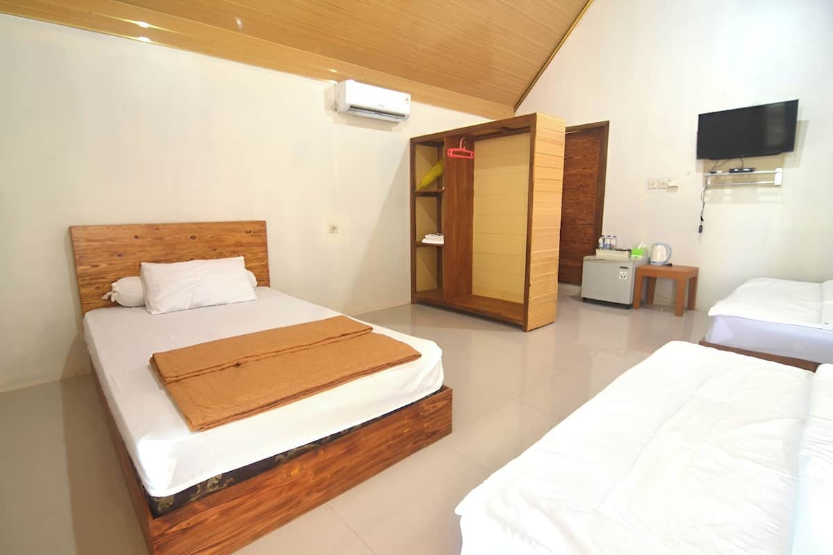 Ein Hotelzimmer mit zwei Betten, einem hölzernen Kopfende, einem Kleiderschrank, einem Fernseher und einer Klimaanlage.