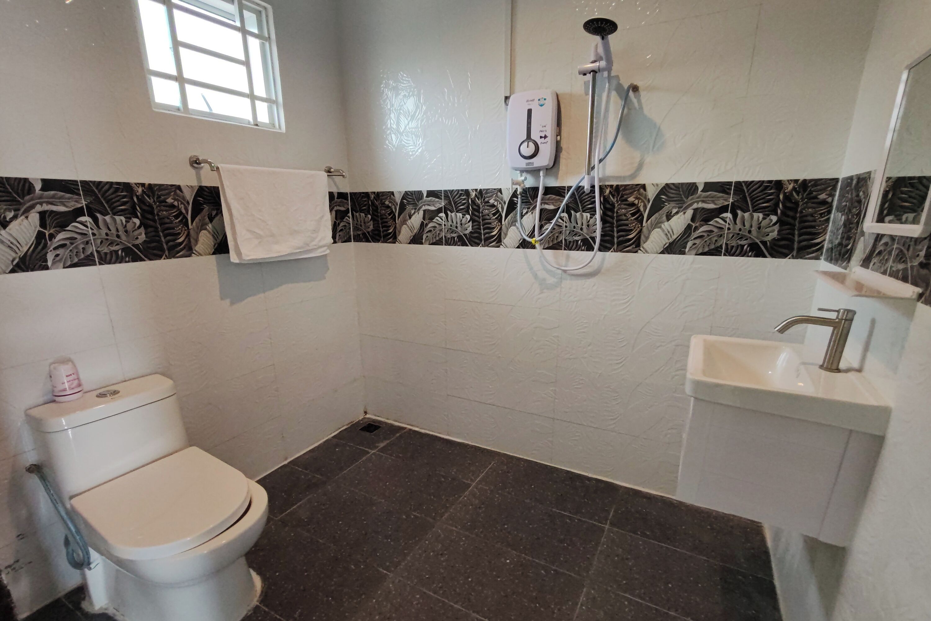 A bathroom with a toilet, a sink, a shower, and a window.