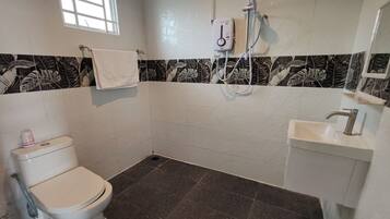 A bathroom with a toilet, a sink, a shower, and a window.