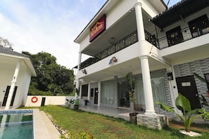 A two-story building with a balcony, a swimming pool, and a garden area.