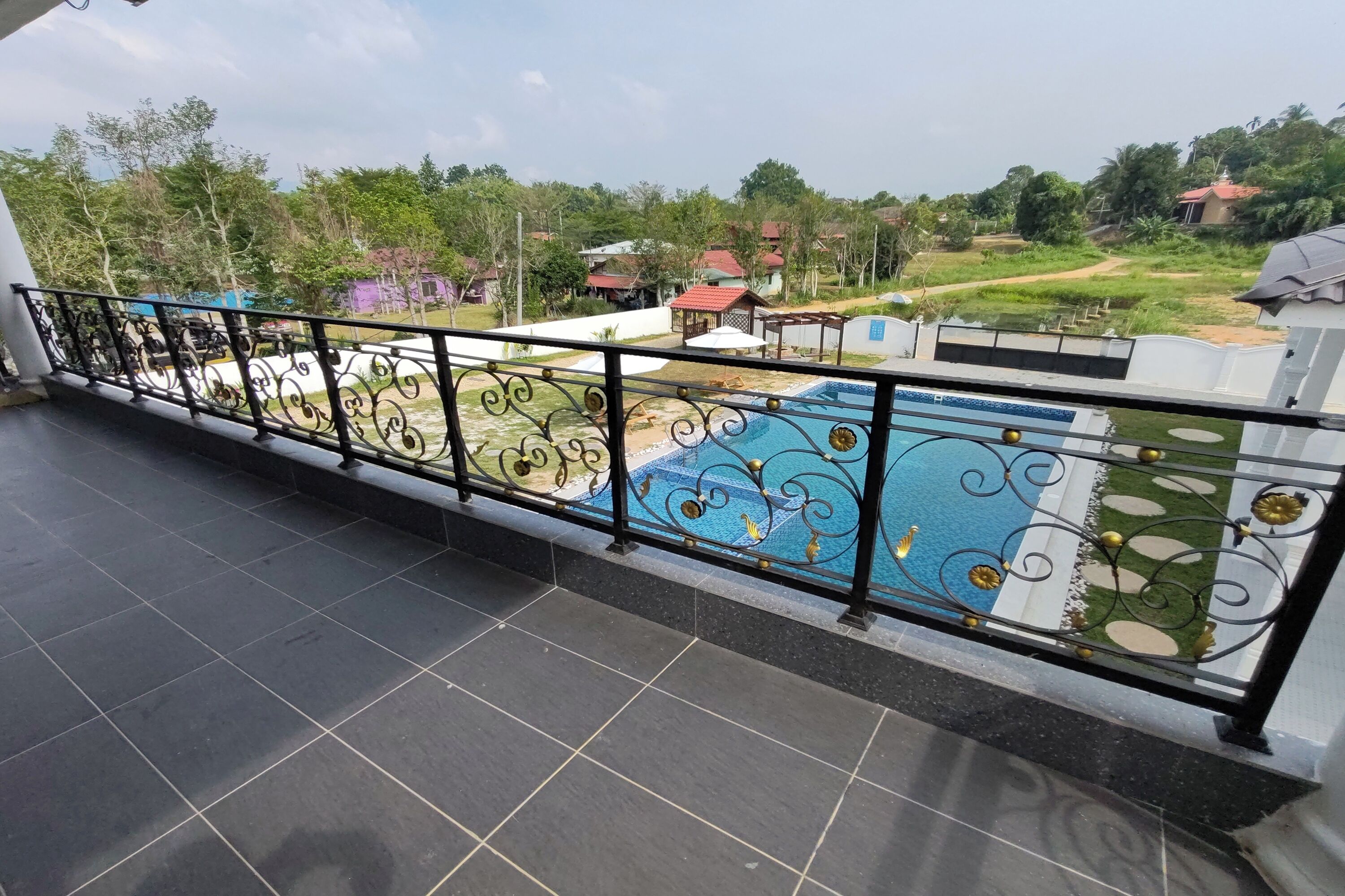 A balcony with a decorative railing overlooking a swimming pool and a view of the surrounding area.