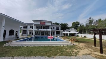 A large, two-story building with a swimming pool in the foreground.