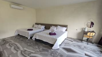 Camera d'albergo con due letti, una scrivania, una sedia e uno specchio.