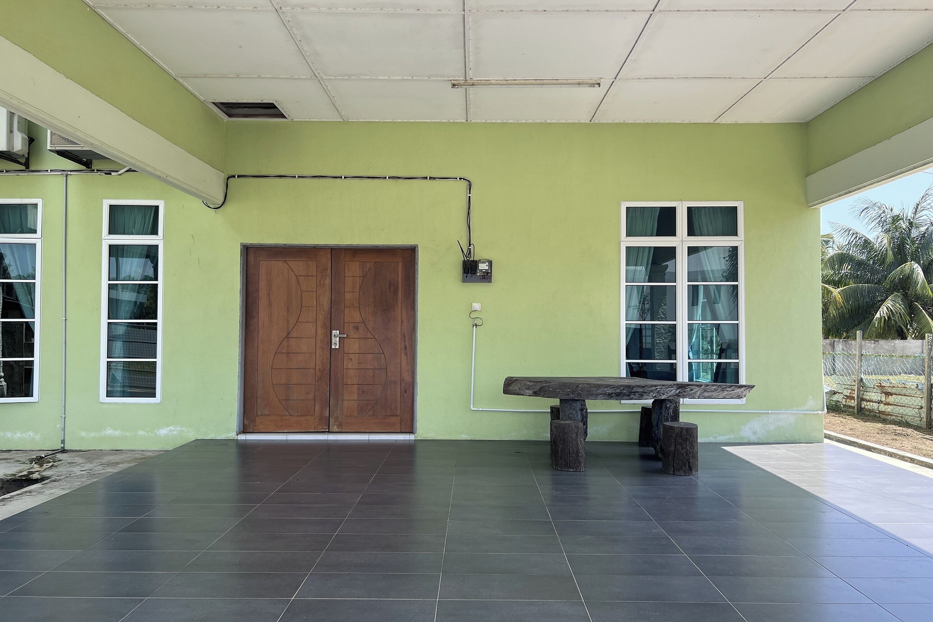 Una habitación con pared verde, puerta de madera y un banco.