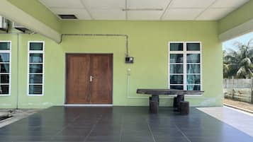 Una habitación con pared verde, puerta de madera y un banco.