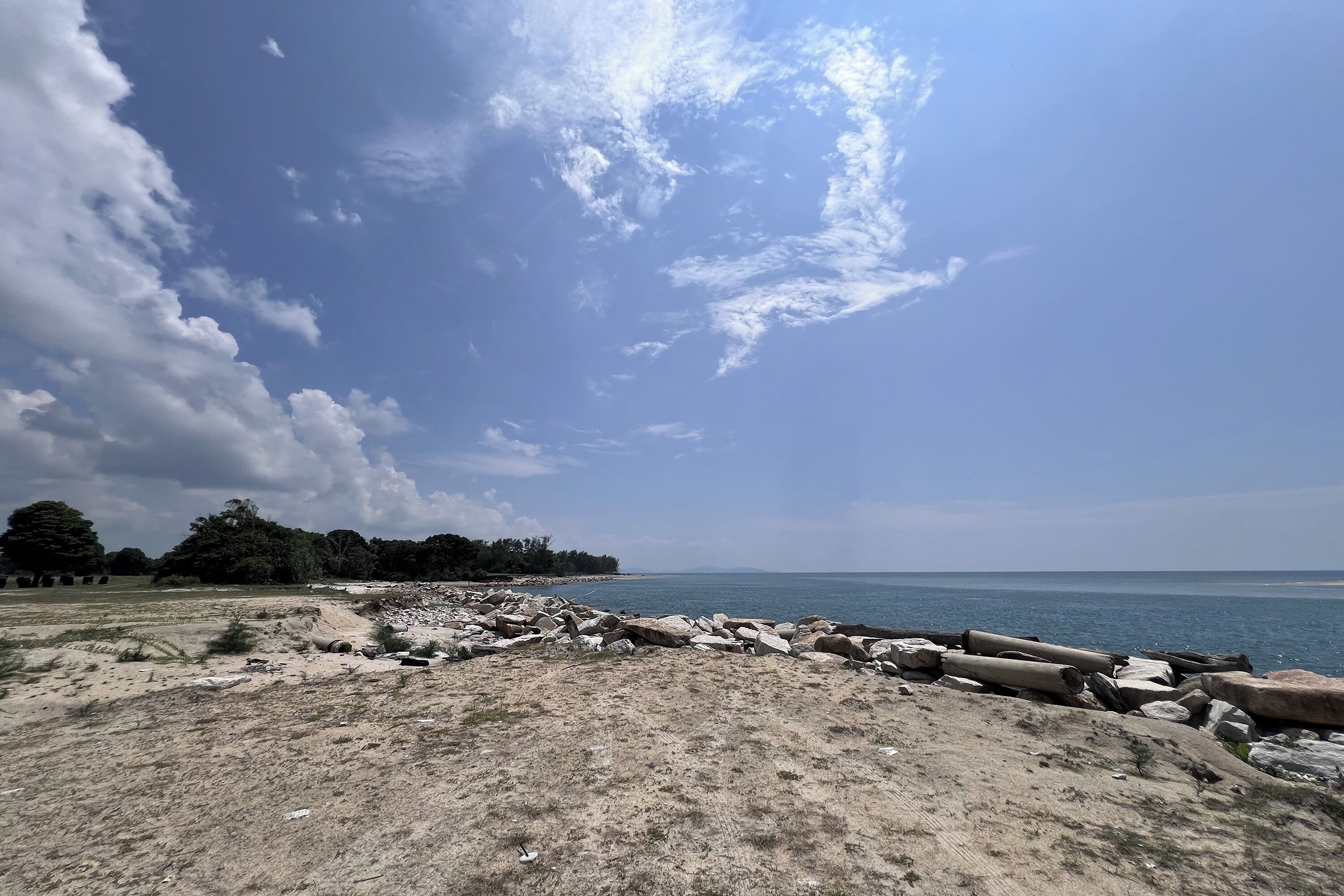 A beach with a rocky shoreline and a clear sky.