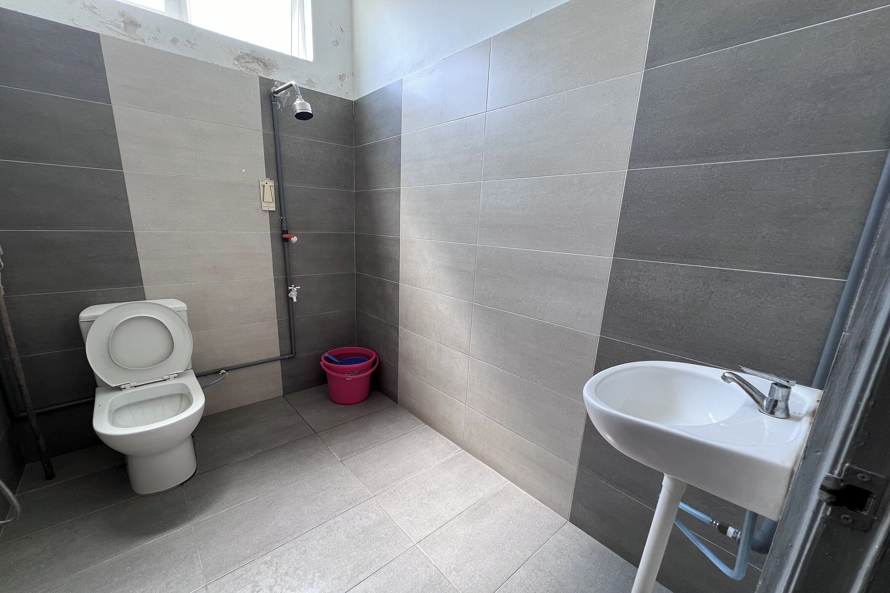 A bathroom with a toilet, shower, and sink.