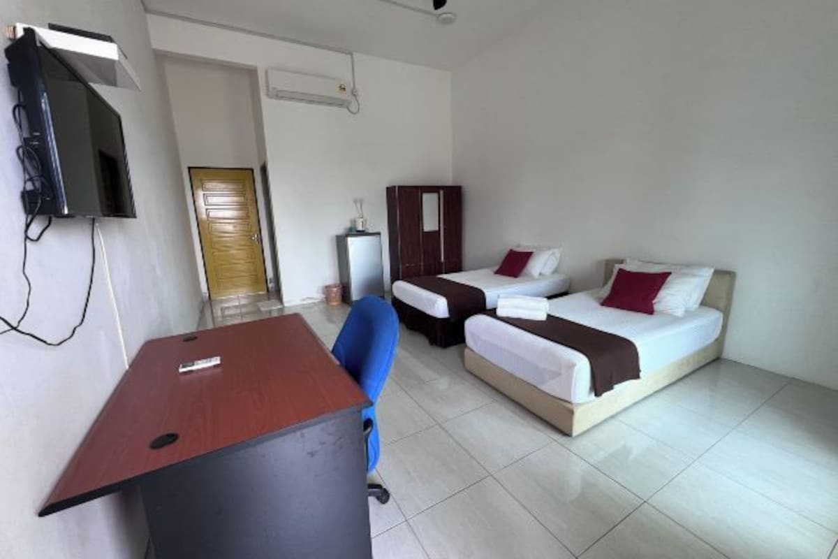 A hotel room with a desk, two beds, a TV, and a wardrobe.