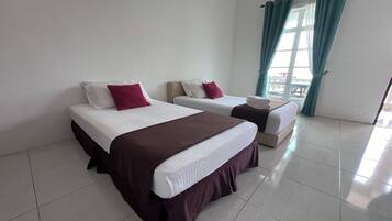 A hotel room with two beds, each with a white mattress and maroon bedding.
