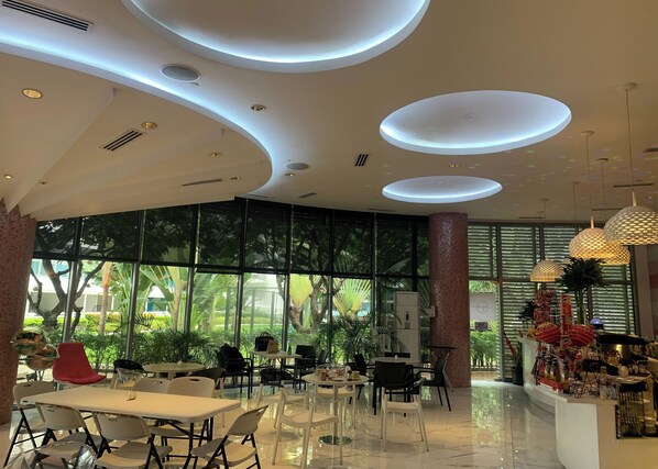 A modern indoor space with large windows, a central seating area, and a decorative column.
