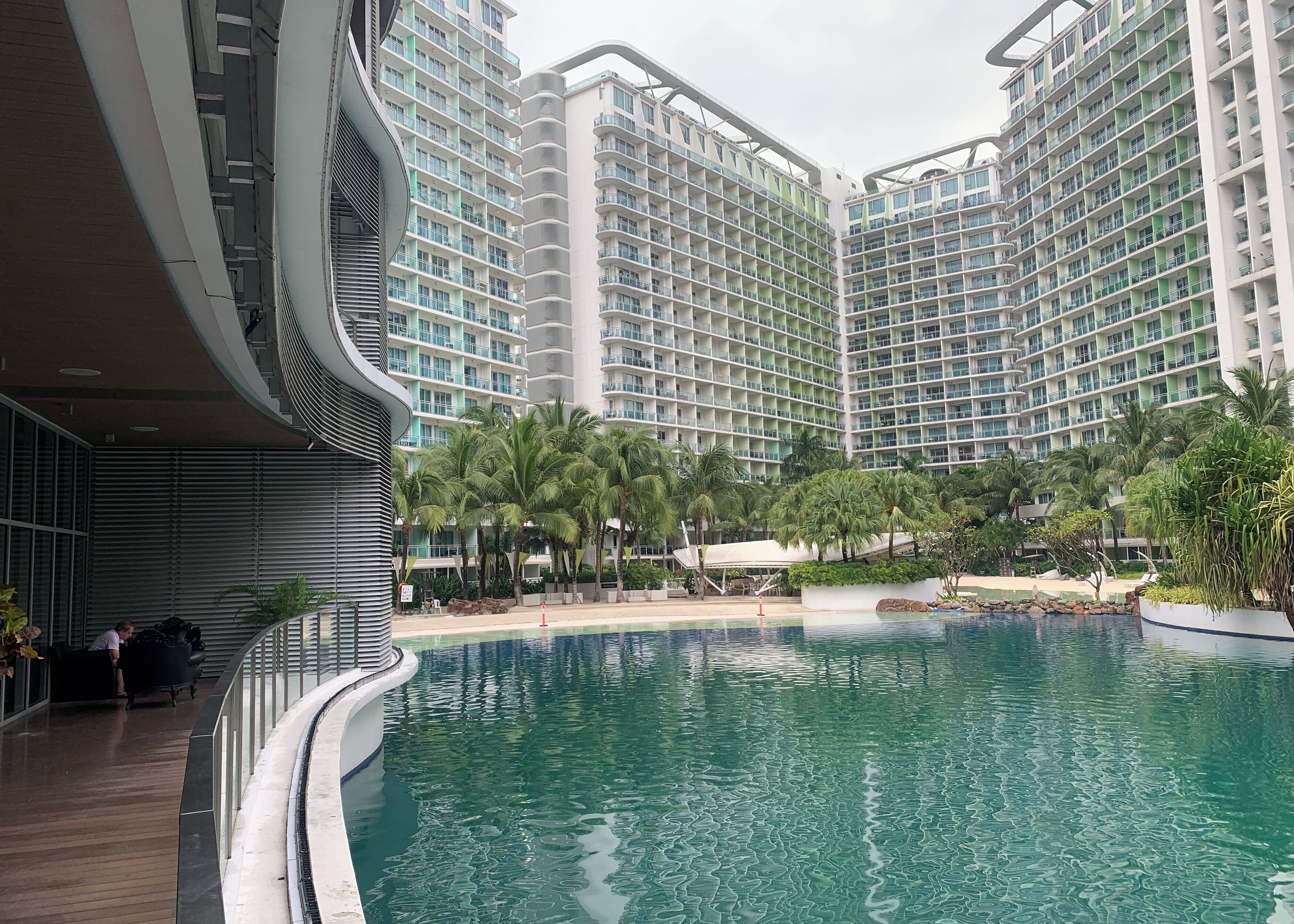 A modern hotel with a pool area, featuring high-rise buildings with balconies and a landscaped garden.