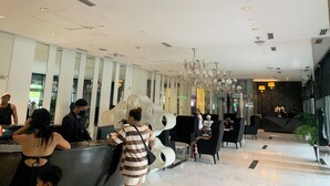 A modern hotel lobby with a reception desk, seating areas, and a chandelier. - Budget Suite Paranaque (Parañaque)