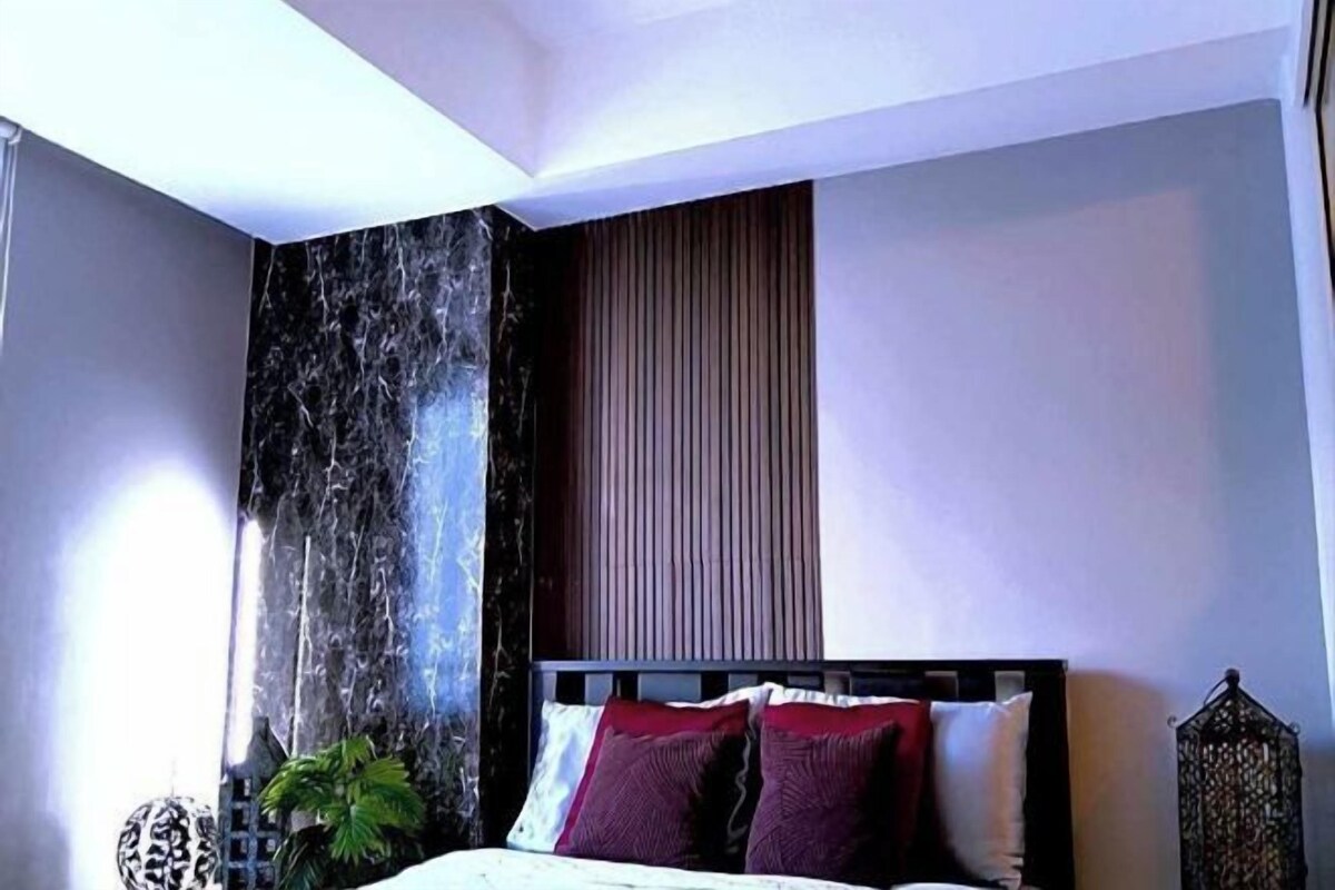 A bedroom with a bed, a wall-mounted water feature, and a potted plant.