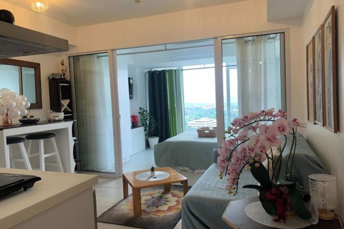 A modern hotel room with a balcony, a dining area, and a bed with a view.