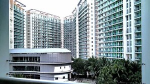 A high-rise residential building with multiple balconies, a swimming pool, and surrounding palm trees. - Budget Suite Paranaque (Parañaque)