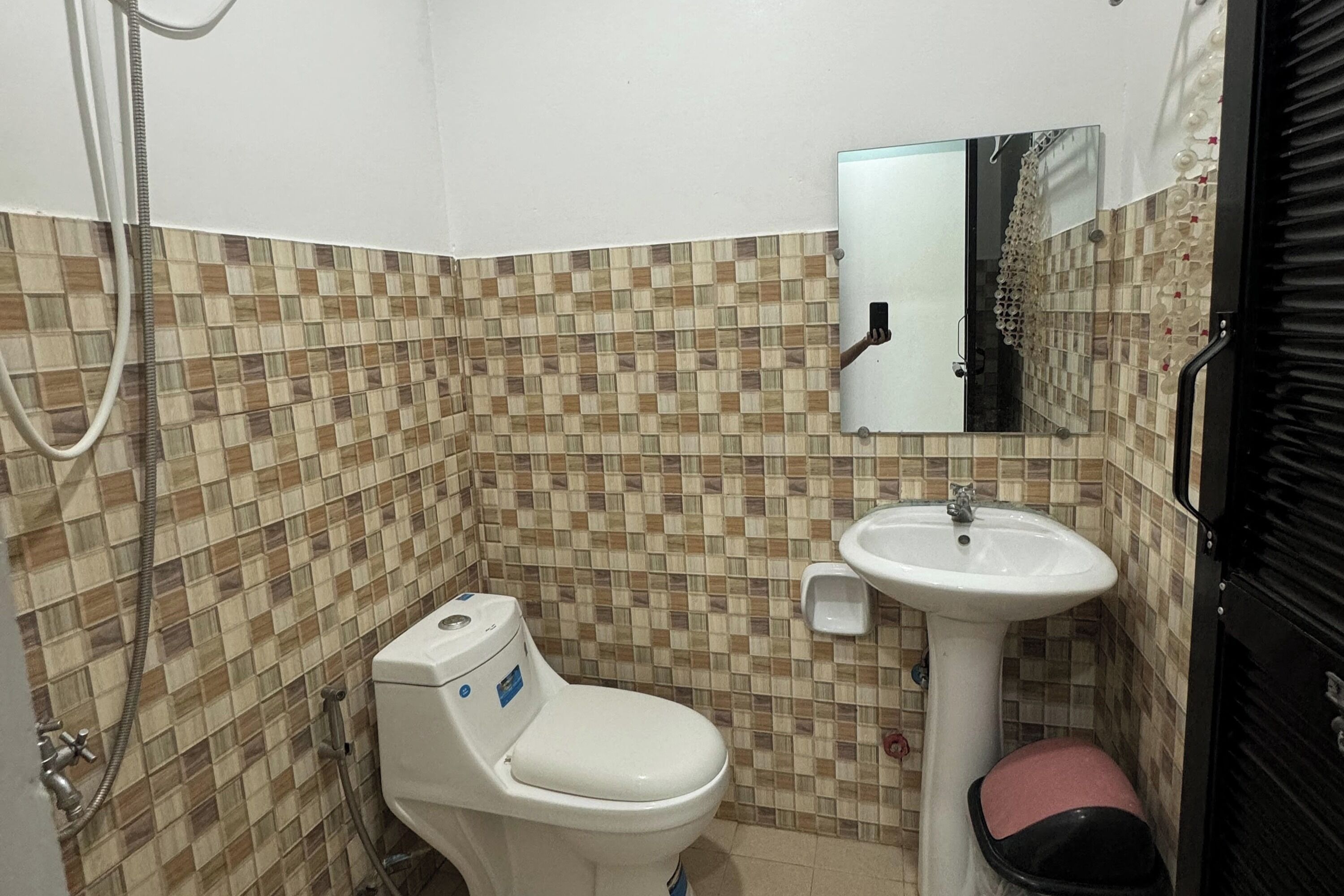 A bathroom with a tiled floor, a toilet, a sink, and a mirror.