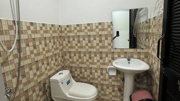 Un baño con piso de baldosas, inodoro, lavamanos y espejo.