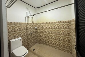 A small, tiled shower area with a toilet. - EC Hotel near Laoag Airport (Laoag)