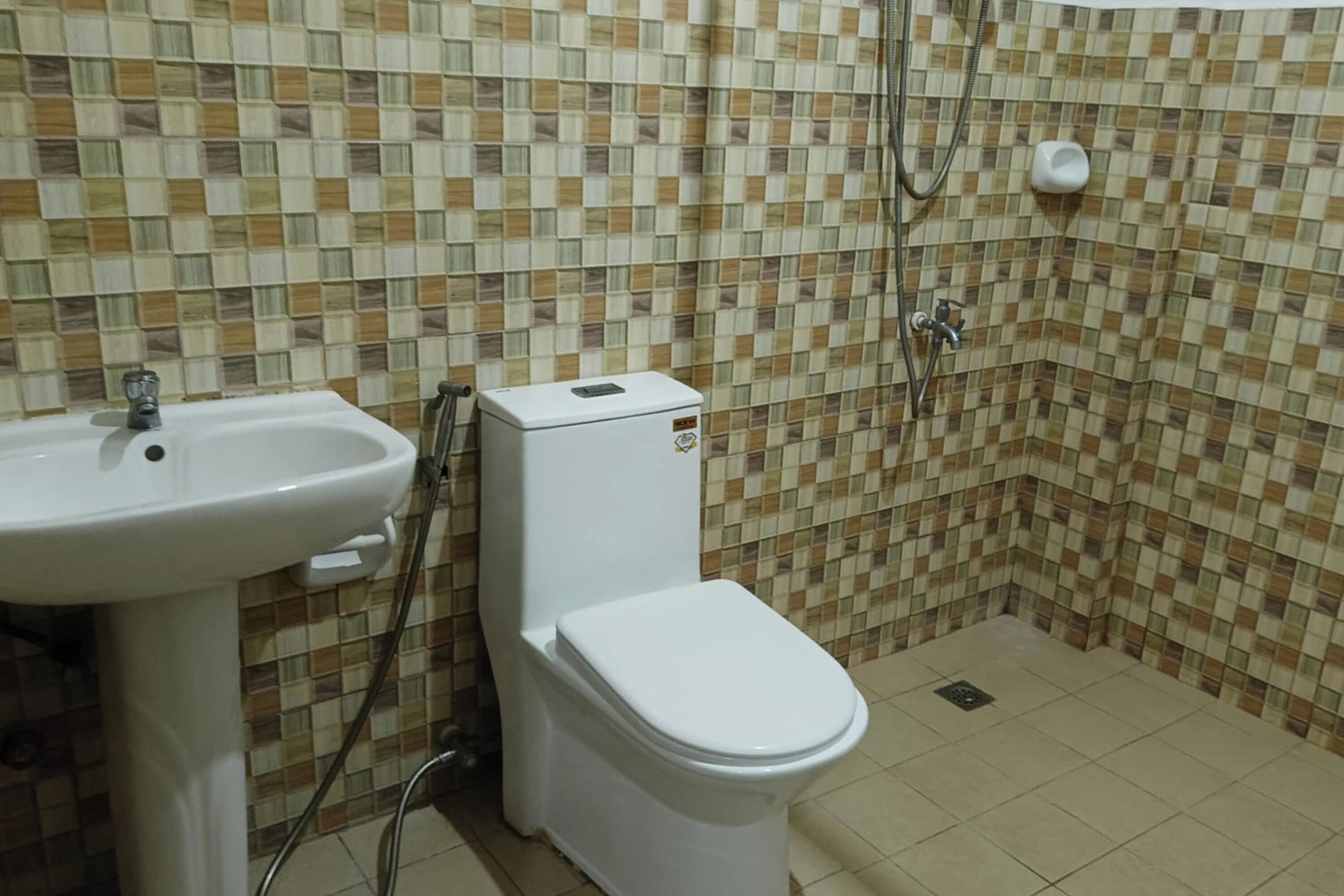 A bathroom with a tiled floor, a white sink, and a toilet.