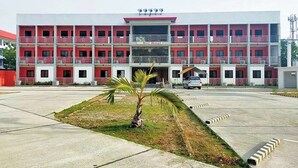 A multi-story hotel with a red and white facade, a central entrance, and a parking lot with a palm tree. - EC Hotel near Laoag Airport (Laoag)