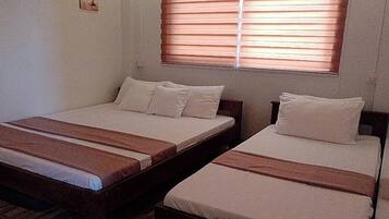 A room with two single beds, each with a wooden headboard and white bedding.