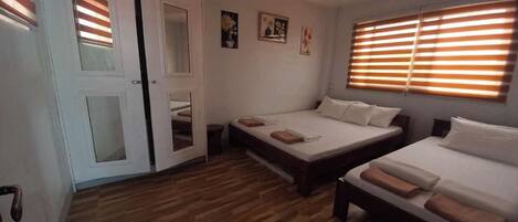Un dormitorio con dos camas, suelo de madera y una puerta con paneles de vidrio.